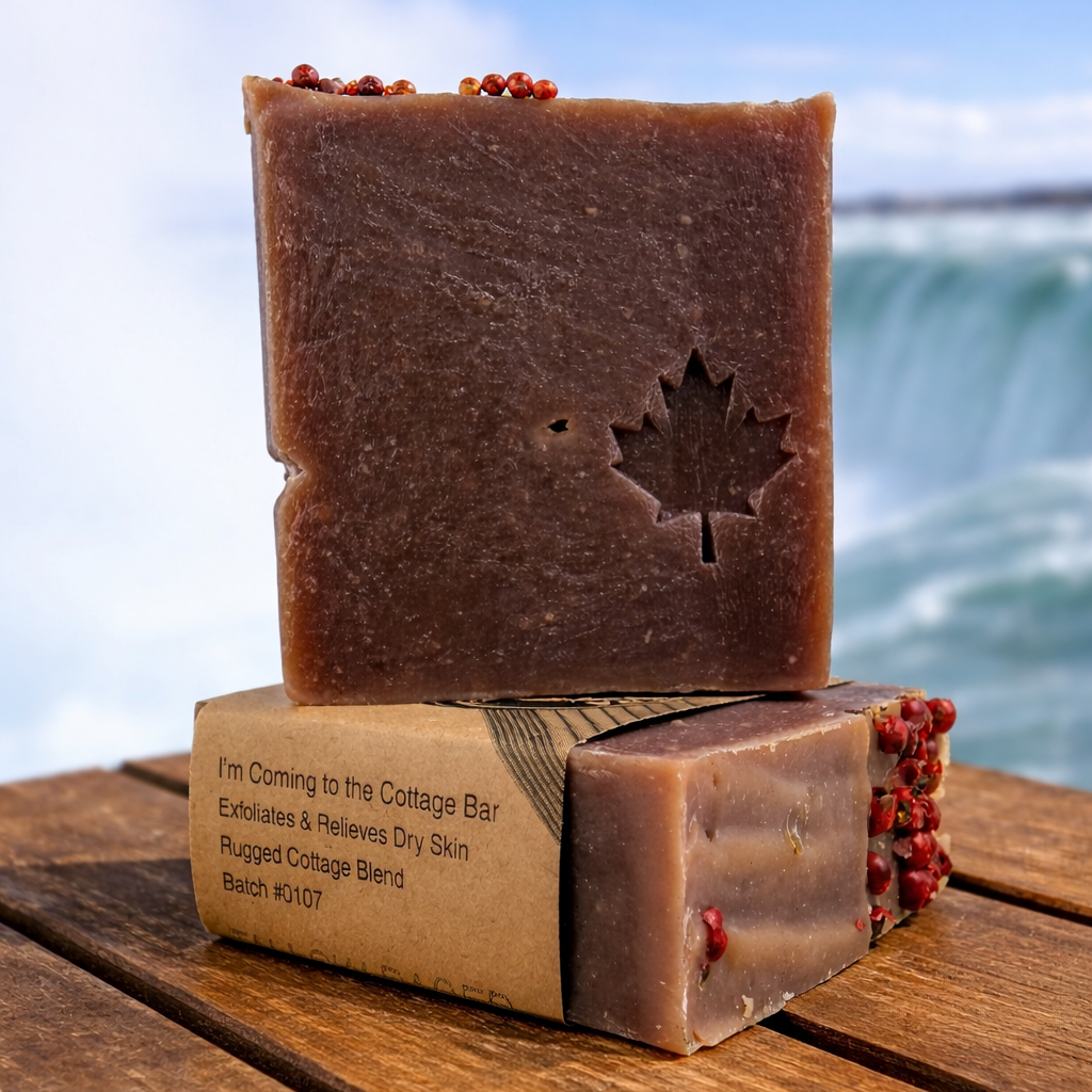 Two bars of soap with a cardboard box featuring a maple leaf design, set against a scenic background.