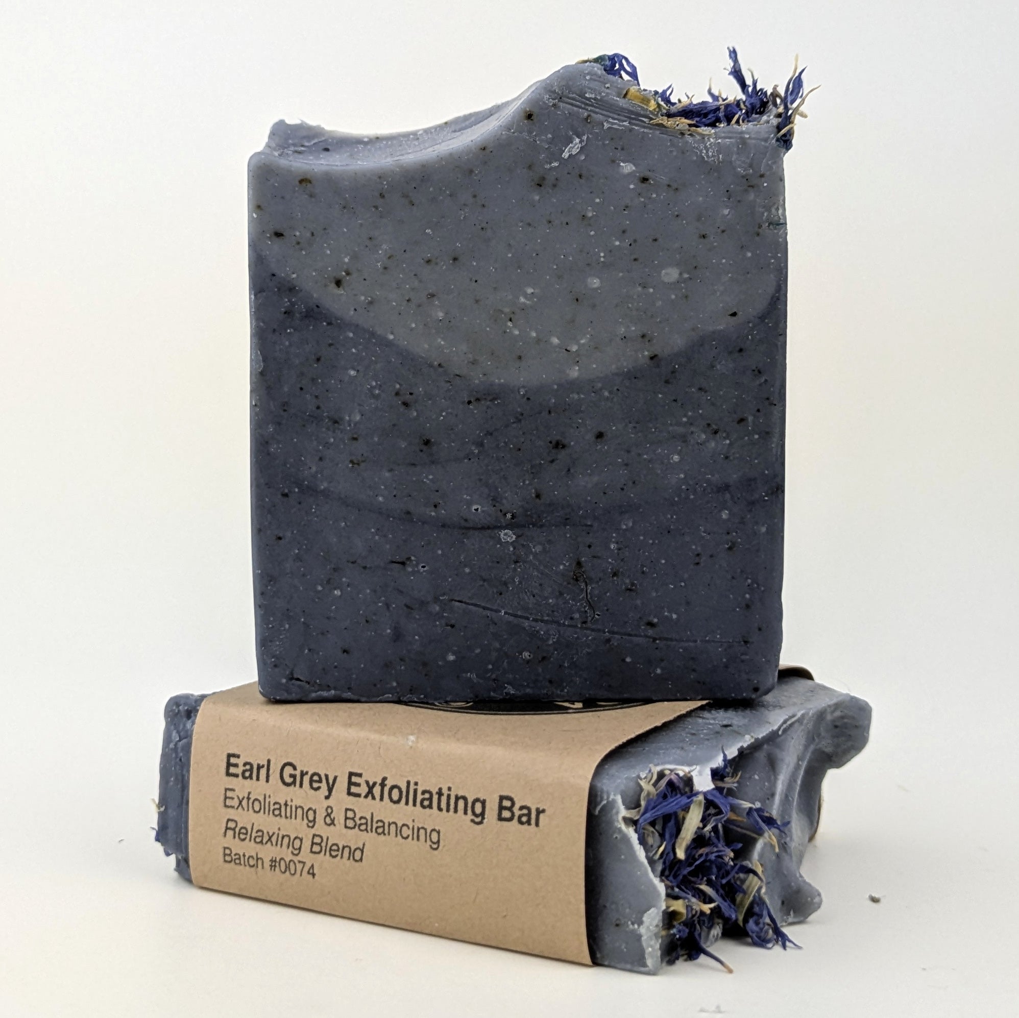 Niagara Craft Soap Earl Grey Exfoliating Bar stacked on itself, one without packaging where the detail can be seen, three layers of gradually denser blue contain flecks of earl grey tea, the whole bar topped with blue corn flower to one side