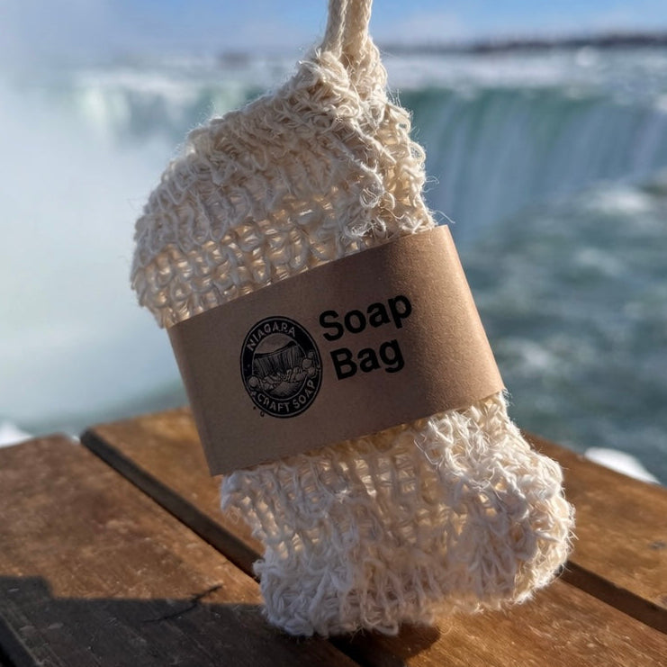Soap bag with a label on a wooden surface with a blurred waterfall background