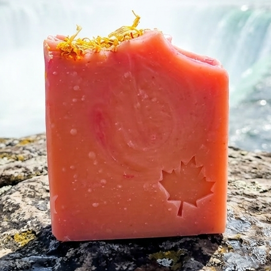 Bar of soap with a logo on a rock in front of a waterfall
