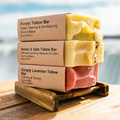 Three tallow bars stacked on a wooden stand with a blurred natural background