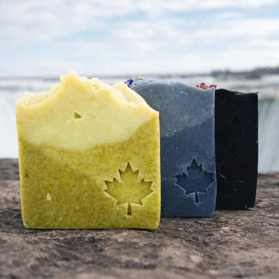 Three bars of soap with leaf cutouts on a wooden surface with a blurred natural background