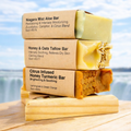 Stack of soap bars with labels on a wooden platform by a scenic waterfront.