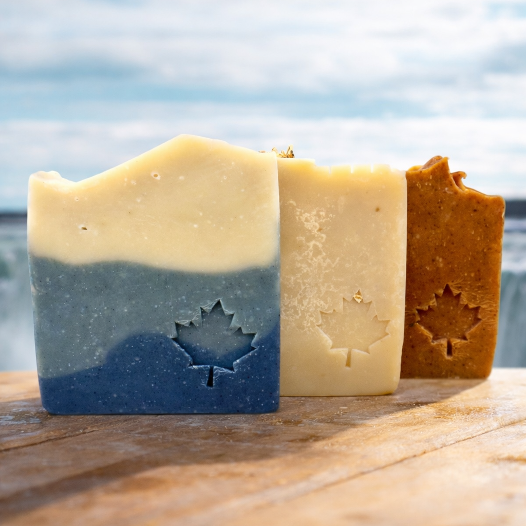 Three bars of soap with maple leaf cutouts on a wooden surface with a blue sky background