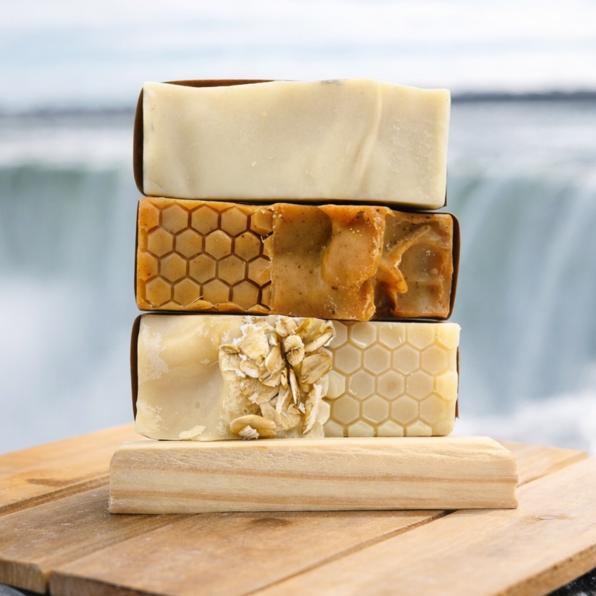 Stack of three soaps on a wooden board with a blurred natural background