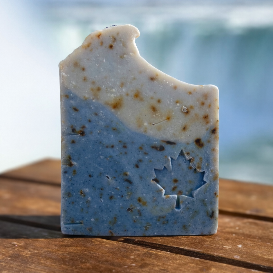 Bar of soap with a maple leaf design on a wooden surface with a blurred natural background