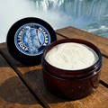 Jar of cream and black container with 'Blue Lagoon' logo on a wooden surface with Niagara Falls in the background