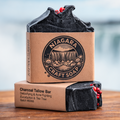 Niagara Craft Soap charcoal tallow bar with packaging on a wooden surface and blurred natural background