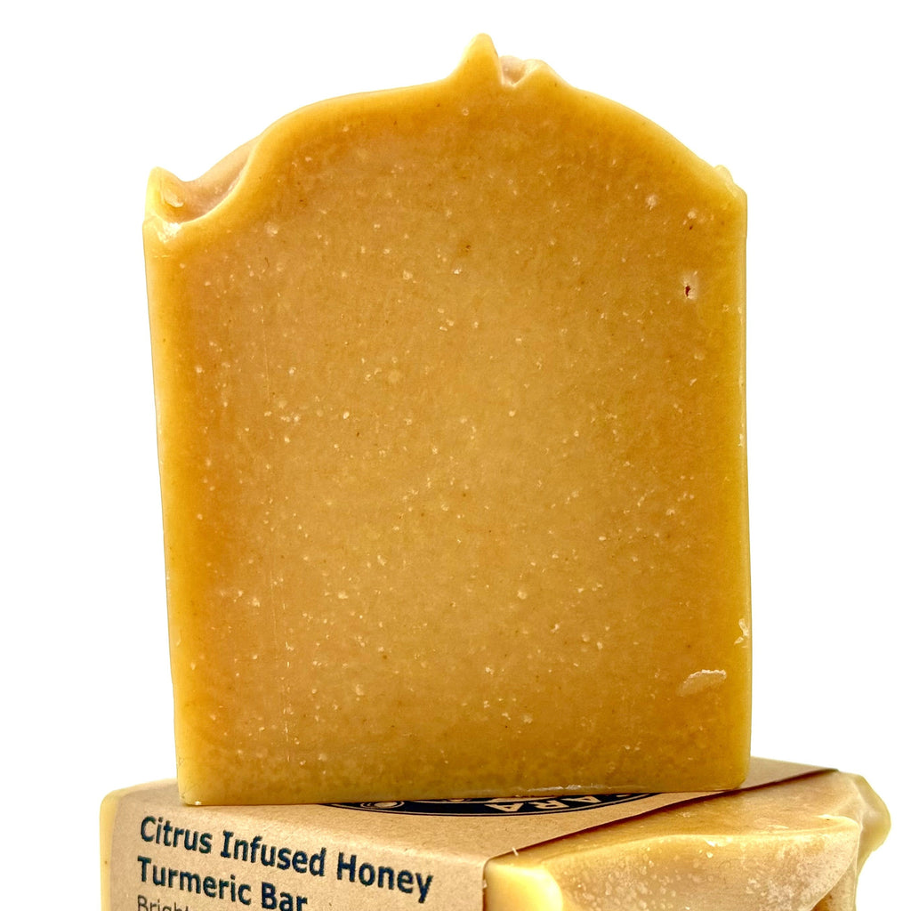 Bar of soap with packaging labeled 'Citrus Infused Honey Turmeric Bar' on a white background