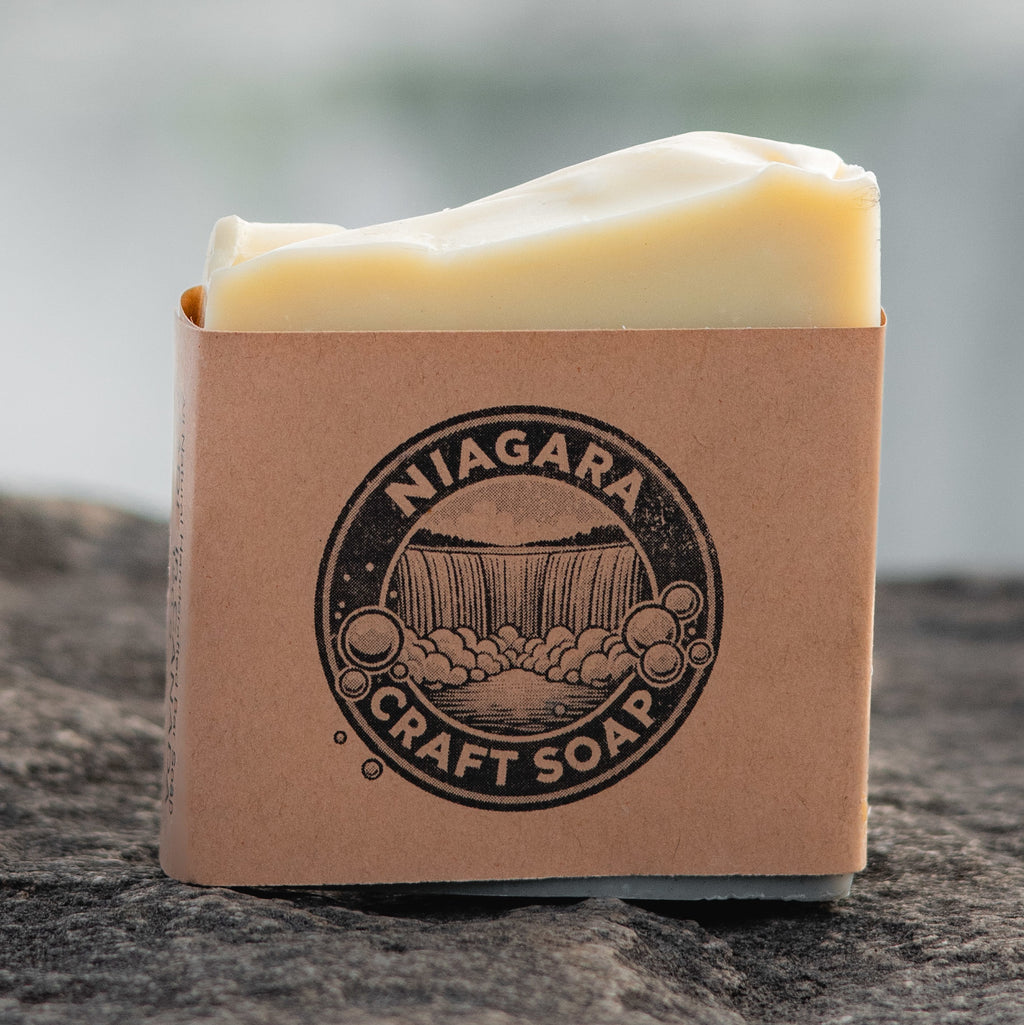 niagara craft soap niagara mist aloe bar soap in kraft paper label showing niagara craft soap logo sitting stone in front of a blurry Niagara Falls Photographer Kurt Casucci
